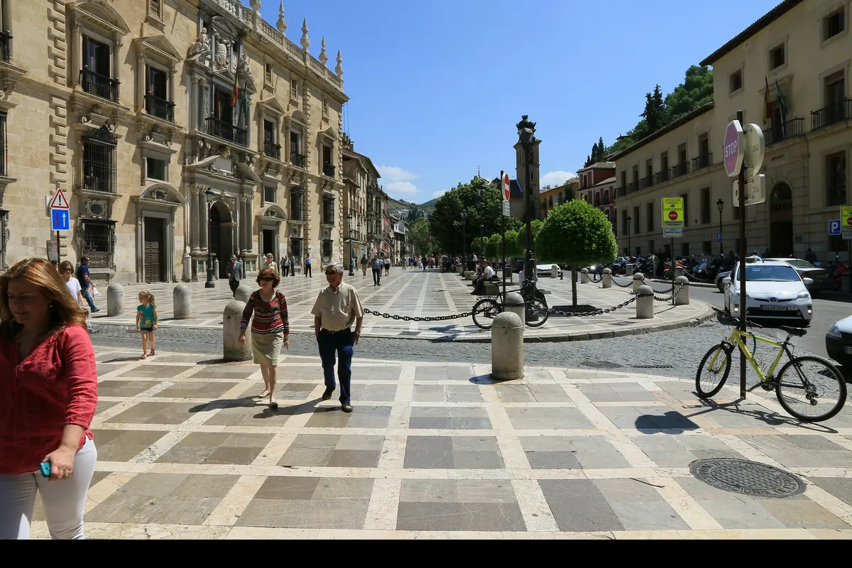 Plaza Nueva in Granada on a sunny day, with the stone facade of the Real Chancillería on the left and the church tower of Santa Ana ahead